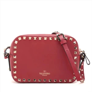 Röd axelväska från Valentino - Snygg röd axelväska från Valentino med nitar runt kanterna. Väskan har en justerbar axelrem och är perfekt för att ge en edgy touch till din outfit. Den är tillverkad i skinn och har en dragkedja för säker förvaring. Skriv privat för fler bilder!!