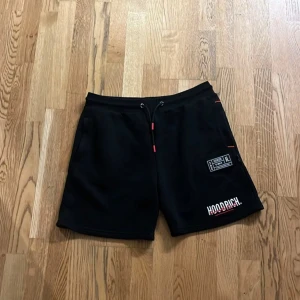 Svarta shorts från Hoodrich - Snygga svarta shorts från Hoodrich med snörning i midjan och coola tryckdetaljer. Perfekta för en avslappnad stil. Använda 3-4 ggr max kn fixa priset vid snabb köp