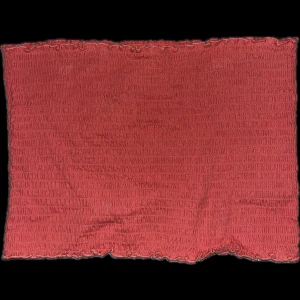 Orange/korallfärgad tubtop - Snygg korallfärgad tubtop  med ett subtilt mönster och vågig kant. Perfekt för att ge lite färg till din outfit. Passar bra till varmare dagar