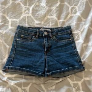 Blå jeansshorts - Säljer ett par klassiska blå jeansshorts från Cubus. De har en normal passform med fem fickor och uppvikta benslut. Perfekta för en avslappnad stil. 🩳