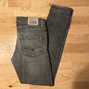 Grå jeans från Replay - Snygga grå jeans från Replay med klassisk femficksdesign och knappgylf. De har en stilren look med Replay-logga på bakfickan och vid linningen. Perfekta för en avslappnad stil.