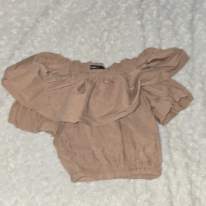 Beige offshoulder topp från Gina Tricot - Säljer en söt beige offshoulder topp från Gina Tricot. Toppen har volangdetaljer och elastiska kanter för en bekväm passform. Perfekt för en somrig look!💞💗