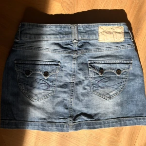 Jeanskjol - Snygg jeanskjol i  blå denim med supersöta fickor!! Står storlek 36 på kjolen och måtten är med på bild :)