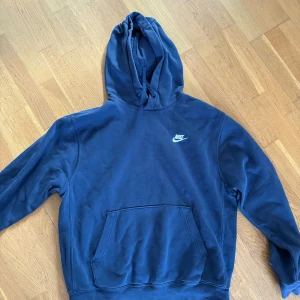 Blå hoodie från Nike - Säljer en snygg blå hoodie från Nike med klassisk logga på bröstet. Tröjan har en stor ficka framtill och en bekväm huva. Perfekt för en avslappnad stil.
