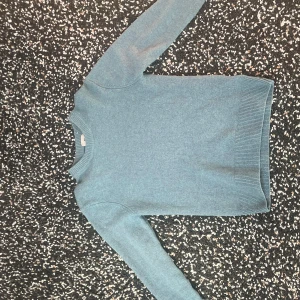 Blå tröja från H&M - Säljer en stilren blå tröja från H&M i regular fit. Tröjan har långa ärmar och ribbade kanter vid ärmslut och nederkant. Perfekt för en avslappnad look.