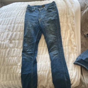 Blå jeans från Lee - Snygga blå jeans från Lee som är väl använda. Dem har blivit lite uppslitna längst ner på benet på grund av att man har trampat på dem. Annars är dem i bra skick 