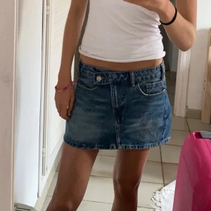 Blå jeanskjol - Snygg blå jeanskjol med klassisk femficksdesign och knappstängning fram. Perfekt för en avslappnad stil. Kjolen har en kort längd och är tillverkad i slitstarkt denim.