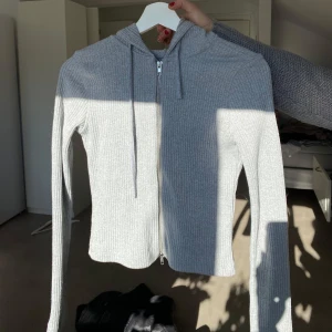 Grå tröja ifrån Gina - Säljer en stilren grå tröja med dragkedja och huva. Perfekt för en avslappnad look. Tröjan har långa ärmar och en bekväm passform.