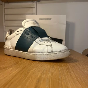 Vit/blå valentino opens - Snygga Valentino Open sneakers i vitt med blå detaljer. Skorna har en klassisk design med snörning och en bekväm sula. Perfekta för en stilren look. De är använda men är fortfarande i ett acceptabelt skick