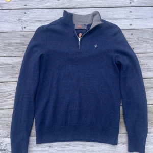 Blå tröja med dragkedja från Morris - Säljer en stilren blå tröja från Morris i merinoull. Tröjan har en dragkedja vid halsen och en liten broderad detalj på bröstet. Perfekt för kyligare dagar med sin mjuka och bekväma passform. Strl m men har krympt så passar mer som S/Xs.