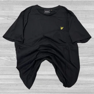 Lyle & Scott - Säljer en stilren svart t-shirt från Lyle & Scott med deras ikoniska gula logga på bröstet. Perfekt för en avslappnad look. T-shirten är kortärmad och gjord i mjuk bomull.