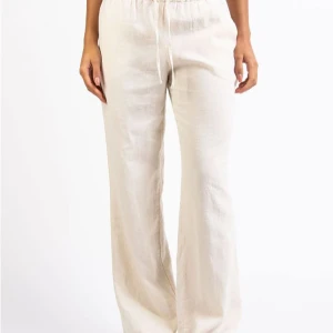 Beige linnebyxor med snörning - Snygga och bekväma beige linnebyxor med snörning i midjan. Perfekta för en avslappnad stil med en loose passform och hög midja. Byxorna har en rak och luftig design som passar bra till varmare väder. Storlek S/regulur. 