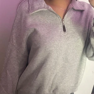 Grå tröja med dragkedja - Säljer en bekväm grå tröja med dragkedja och krage. Tröjan har långa ärmar och ribbade muddar vid ärmslut och nederkant. Perfekt för en avslappnad stil. Den är jätte mjuk att ha på sig 