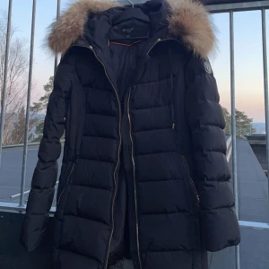 Svart dunjacka med pälsdetalj från Hollies - Svart dunjacka från Hollies, storleken är 42 men den är som en 38 på. Nypris 3500. Endast använd en säsong.
