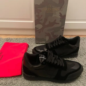 Svarta Valentino rockrunners - Snygga svarta Valentino rockrunners med en diskret camouflage-design. Skorna har snörning och är tillverkade i en kombination av skinn och syntetmaterial. Perfekta för en stilren look. Köpta här på plick och passade mig ej. Hör av er för fler frågor!
