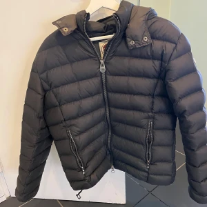 Colmar jacka  - Säljer en snygg svart pufferjacka från Colmar. Jackan har en dragkedja framtill och praktiska fickor med dragkedjor. Den är quiltad och har en avtagbar huva. Perfekt för kyliga dagar! En liten defekt därför så billigt pris. 😁