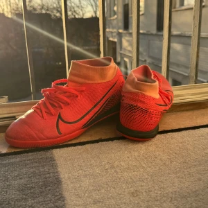 Nike fotbollsskor  - Snygga röda rosa Nike fotbollsskor med svart logga. Skorna har en tight passform och är perfekta för inomhusspel. De har en elastisk krage för extra stöd runt ankeln. Dock saknar den en insole. Skick 8/10 Strlk 41