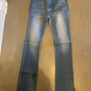 Blå jeans med slits - Snygga blå jeans med bootcut-stil och slits vid bensluten. De har en klassisk femficksdesign och stängs med knapp och dragkedja. Perfekta för en avslappnad look. De är från Shein i storlek XS jätte fina med slits längst ner 