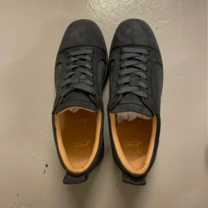 Snygga Louboutin skor - Snygga svarta sneakers från Christian Louboutin med den ikoniska röda sulan. Skorna har en stilren design med snörning och är tillverkade i mocka. Perfekta för dig som vill ha en lyxig touch på vardagslooken. Dm för frågor. Pris kan diskuteras