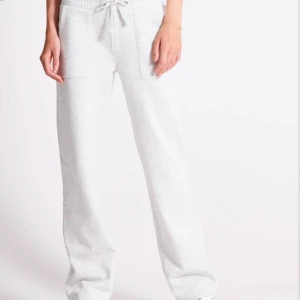 Ljusgrå mjukisbyxor - Säljer ett par ljusgrå mjukisbyxor med resår och dragsko i midjan. Byxorna har raka ben och stora fickor framtill samt en bakficka. Perfekta för en avslappnad stil.