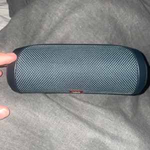 Mörkblå JBL Flip 4 Bluetooth-högtalare - Säljer en mörkblå JBL Flip 4 Bluetooth-högtalare. Kompakt och portabel design med tydligt JBL-logga på framsidan. Perfekt för att ta med sig musiken överallt. Laddas enkelt och har smidiga knappar på baksidan. laddare får man med sig