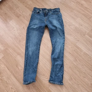 Levi's 502 blå jeansbyxor W28/L32 - Klassiska blå Levi's 502 jeans med normal passform och raka ben. Jeansen har fem fickor, dragkedja och knapp i midjan samt tydliga Levi's-detaljer som läderpatch och röd etikett bak. Endast använda ett par gånger så i princip nyskick. Annonsen ligger även ute på Vinted så kolla så dom finns kvar innan ni trycker på köp. 