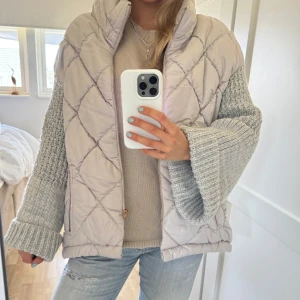 Beige quiltad jacka med stickade ärmar - Säljer en beige quiltad jacka med ljusgrå stickade ärmar. Jackan har dragkedja framtill och två fickor med dragkedja. Perfekt för lager-på-lager och passar utmärkt till vår och sommar❣️❣️
