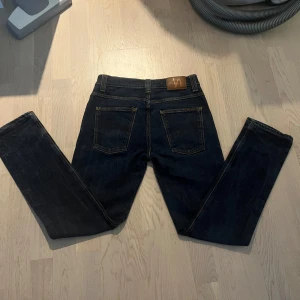 Nudie Jeans - Säljer ett par klassiska blå jeans från Nudie Jeans i modellen Grim Tim. Jeansen har raka ben, fem fickor och är tillverkade av 99% ekologisk bomull och 1% elastan. Snygga kontrastsömmar och normal passform.