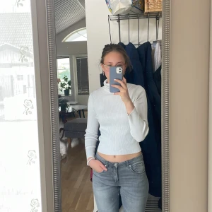 Vit ribbad polotröja  - Säljer en vit ribbad polotröja från H&M. Tröjan är tight och croppad med långa ärmar och hög krage. Perfekt att styla med jeans eller kjol för en enkel och snygg look.