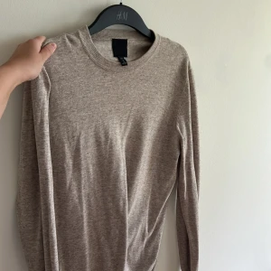 Beige stickad tröja från H&M - En enkel och stilren beige stickad tröja från H&M med rund halsringning och långa ärmar. Perfekt för lager-på-lager och passar till många olika outfits.