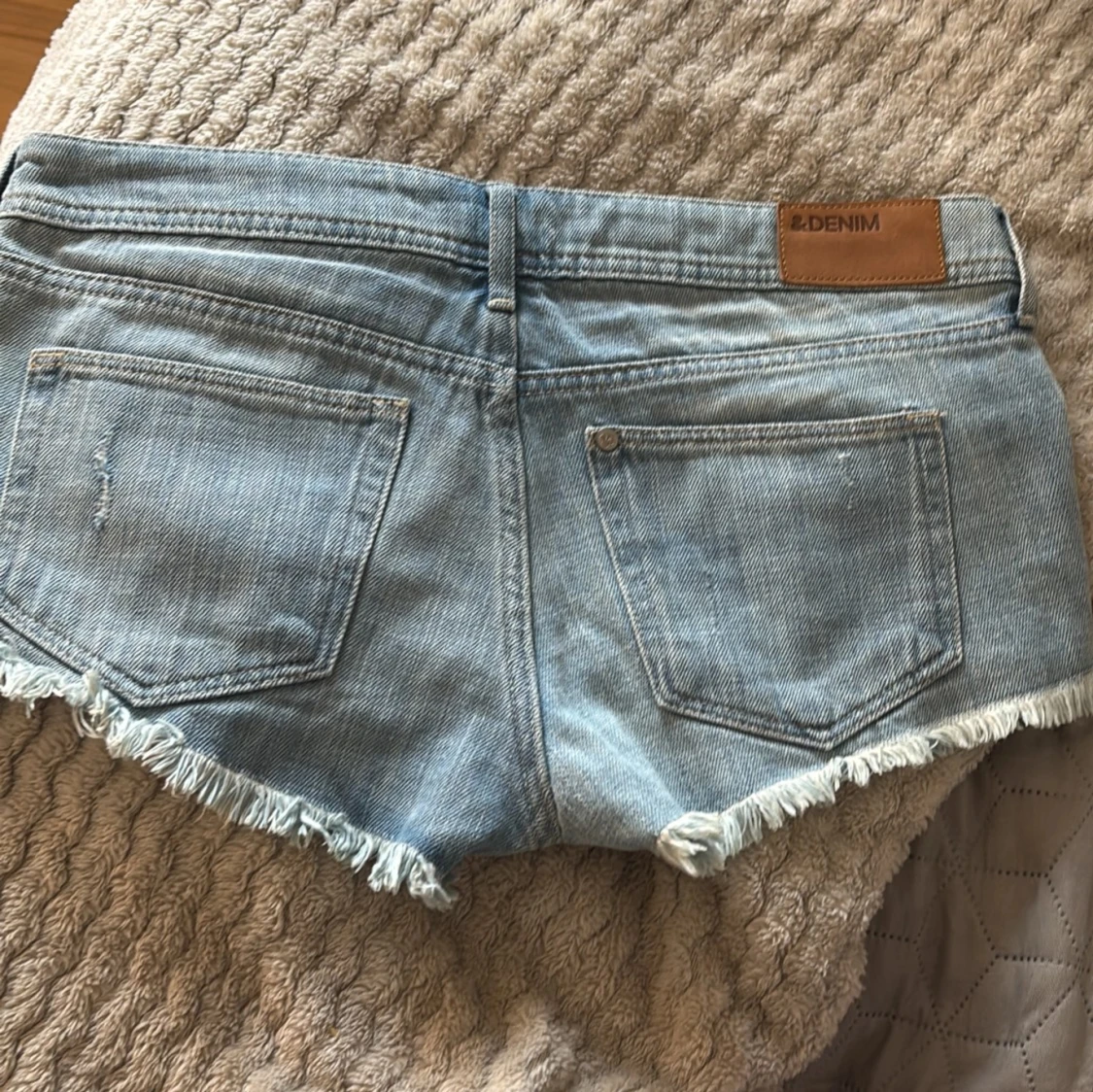 Ljusblå lågmidjade jeansshorts med fransar och paisleydetaljer
