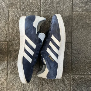 Adidas Gazelle blå - Säljer nu mina blå adidas gazelle då de inte längre passar. De är i storlek 42 och har inga skador. Priset går att diskutera. Hör av dig om du har några frågor!
