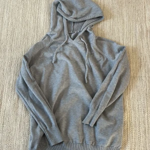 Grå merinoull hoodie - Säljer en helt ny grå merinoull hoodie med huva och dragsko. Den har storlek M men passar S och XS (för de som är 165-172)