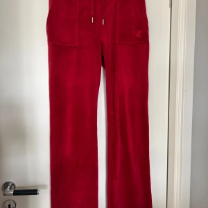 Röda byxor från Juicy Couture - Säljer ett par  röda byxor från Juicy Couture med raka ben och resår och snörning i midjan. Byxorna har fickor fram och bak med knappar. Lite använda men inga tydliga slitage.