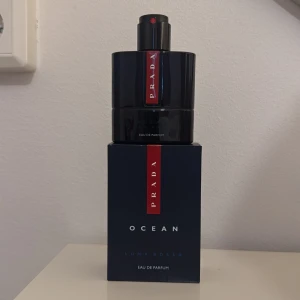 Prada Luna Rossa Ocean Eau de Parfum - En elegant parfym från Prada, Luna Rossa Ocean Eau de Parfum. Flaskan är 50ml men innehåller cirka 43 ml kvar. Flaskan är mörkblå med en röd vertikal logotyp och svart spraykork. Doften är modern och fräsch, perfekt för dig som gillar exklusiva och marina toner, även perfekt nu inför sommaren! 