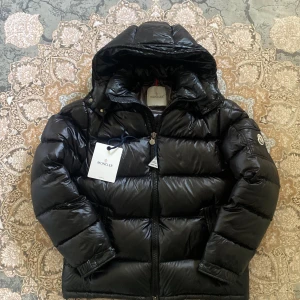 Svart Moncler Maya - Säljer en svart Moncler Maya, säljer billigt eftersom den är använd i ca 3 månader men även att det börjar bli varmare och är ej vid behov av den längre. Storleken är 2 och det är ungefär M. Priset kan diskuteras. NFC och QR Kod Skannas! Inköpsbevis finns ej kvar!