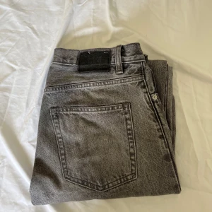 Grå jeansbyxor från 157 - Säljer ett par grå jeansbyxor från 157 med klassisk femficksdesign och dragkedja. Jeansen har en rak passform och är tillverkade i denim. Perfekta för dig som gillar en enkel och stilren look.
