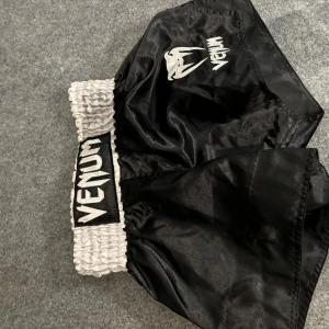 Svarta träningsshorts från Venum - Säljer ett par svarta träningsshorts från Venum. Detta är mer muy thai shorts men funkar till mma också. Märkte att de var för små direkt när jag fick dom. Var en present så hann därför inte lämna tillbaka de. Använda knappt en gång. Nypris gick på cirka 600 kr.