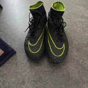 Nike hypervenom fotbollsskor svart/gul - Säljer ett par Nike hypervenom fotbollsskor i svart med gula detaljer och snörning. Skorna har hög krage och är designade för bra grepp på planen. Perfekta för dig som vill ha snabba och lätta skor med snygg look.