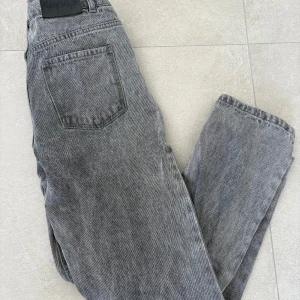 Grå jeansbyxor från RYVLS - Säljer ett par grå jeansbyxor från RYVLS i klassisk femficksmodell. Byxorna har raka ben och normal passform, perfekt för dig som gillar en enkel och stilren look. Snygga till både sneakers och boots. Litet hål ( se bild )