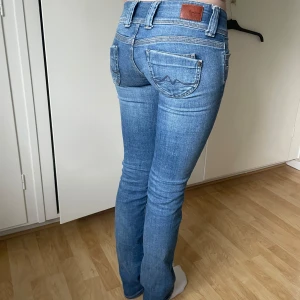 Blå straight jeans från Pepe Jeans - Snygga blå jeans från Pepe Jeans med straight fit och låg midja. Dubbla knappar framtill och detaljerade bakfickor. Perfekta till vardags för en avslappnad men stilren look. Jeansen har storlek W27/L34💗💗