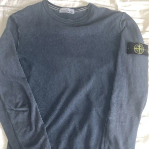 Blå långärmad tröja från Stone Island - Säljer en blå långärmad tröja från Stone Island med klassisk rund halsringning och den ikoniska loggan på vänster ärm. Funkar för storlek M och S. Tröjan har en enkel och stilren design, perfekt för dig som gillar streetwear och snygga basplagg. Kom gärna med prisförslag. 