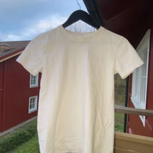Vit t-shirt från Mywear Kids - En klassisk vit t-shirt från Mywear Kids med rund hals och korta ärmar. Perfekt basplagg i mjuk bomull som passar till det mesta. Enkel och stilren design utan tryck eller mönster.
