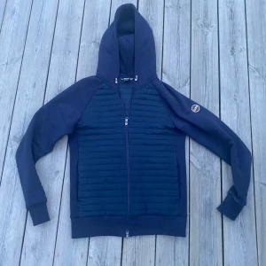 Mörkblå cardigan från Colmar - Säljer en mörkblå cardigan från Colmar i storlek S👏 Jackan har dragkedja, huva och ribbade muddar. Cardiganen är använd 2 gånger så skicket är väldigt bra🤝 Perfekt för dig som vill ha en jacka för våren och sommaren.