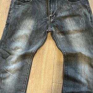 Svarta jeans från Dolce & Gabbana med slitningar - Säljer ett par svarta jeans från Dolce & Gabbana med snygga slitningar och tvättad look. Jeansen har klassisk femficksdesign, silverfärgade knappar och tydlig logotyp bak. Perfekta för dig som vill sticka ut med en exklusiv stil.