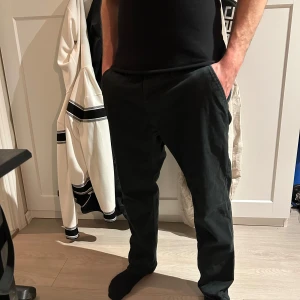 Svarta chinos från dressman  - Säljer ett par svarta chinos från dressman Byxorna har normal passform, raka ben och klassisk design med fickor fram och bak. Perfekta för en stilren och enkel look.