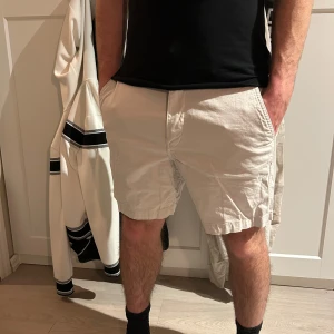 Vita shorts från Gant - Snygga vita shorts från Gant med klassisk design och normal passform. Shortsen har fickor fram och bak samt dragkedja och knapp i midjan. Perfekta för varma dagar och enkel att matcha med olika outfits.