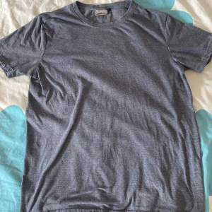 Grå/blå  T-shirt  från Etirel i bomull - Säljer En schysst  basic blå t-shirt från Etirel i storlek S. T-shirten har rund halsringning och korta ärmar. Tillverkad i mjuk bomullsmix med polyester för extra komfort. Perfekt till jeans eller shorts för en chill look. Hojta till ifall ni vore intresserad samt har övriga frågor! 