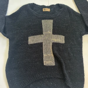 Svart stickad tröja med kors - Stickad tröja med ett guldigt korst i mitten! Storlek s/m.
