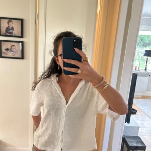 Vit kortärmad skjorta från Lindex - Säljer en luftig vit skjorta från Lindex i storlek M. Skjortan har korta ärmar, knappar framtill och är gjord i ett mjukt, strukturerat bomullstyg. Perfekt för en chill och avslappnad stil.